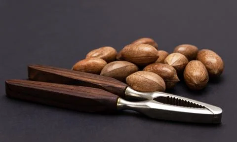 Three pecan nuts and nutcracker, isolated on white background. Stock Photos