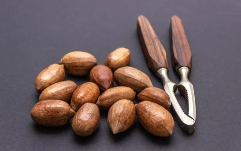Three pecan nuts and nutcracker, isolated on white background. Stock Photos