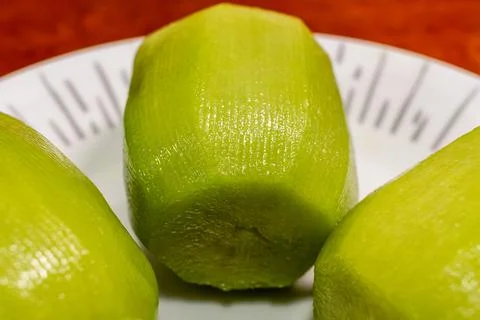 Three peeled kiw ifruits on a patterned white plate on wooden table, close-up. Stock Photos