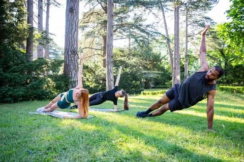 Three people are doing high side plank hold a park training together Stock Photos