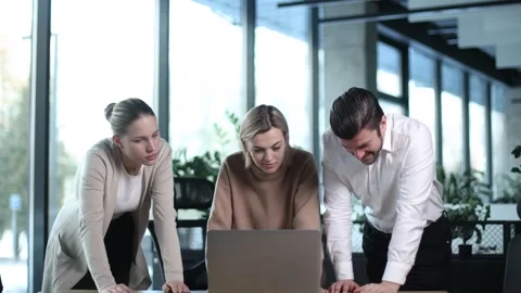 Three people are standing around a laptop computer, looking at the screen Stock Footage 329867084