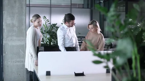Three people are standing in front of a white desk with a computer monitor on it Stock Footage 329850876