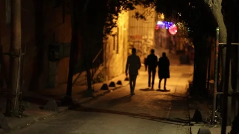 Three people are walking down a deserted street at night. Stock Footage 247504916