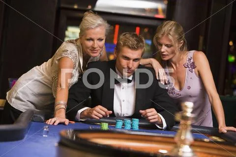 Three people in casino playing roulette smiling (selective focus) Stock Photos