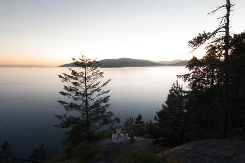 Three people on cliff while Sunset on coast Stock Photos