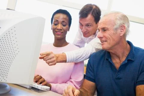 Three people at a computer terminal (depth of field/high key) Stock Photos
