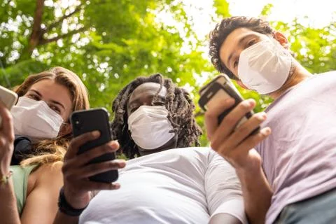 Three people of different ethnicities standing together with a mobile phone i Stock Photos