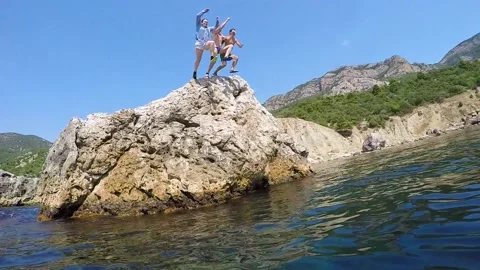 Three people diving from the cliff holding hands. Slow motion. Stock-Footage 85937560