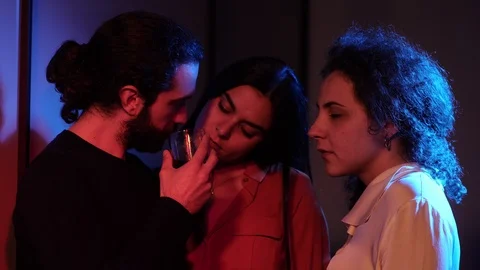 Three people drinking,flirting in the dark night club.Polygamy, threesome Stock Footage 103537103