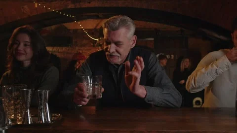 Three people drinks at the bar counter. Caucasian adult male enjoying a drink Stock Footage 253628209