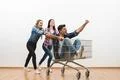 The three people fun with a shopping cart on a white wall background Photo