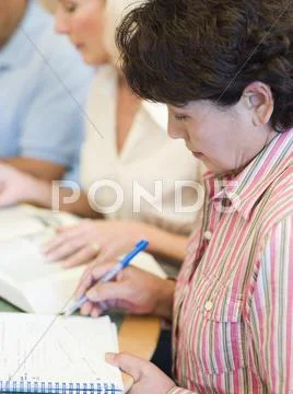 Three people in library with books and notepads (selective focus) Stock Photos