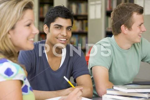 Three people in library studying (selective focus) Stock Photos