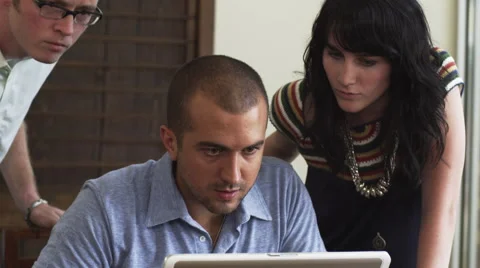 Three people look at a laptop Stock Footage 62916477