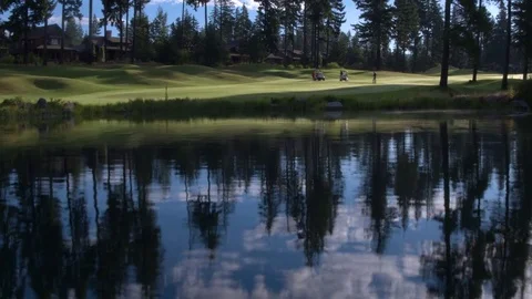 Three people playing golf by a lake Stock-Footage 76236500