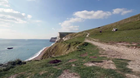 Three people sitting on a cliff looking at the sea Stock Footage 57356183