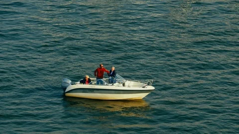 Three people on a small boat in a safe harbor awaiting rescue from off Stock Footage 111289571