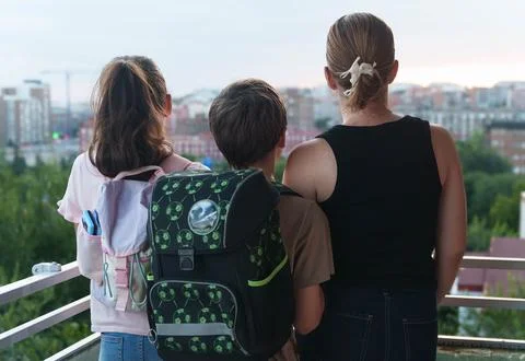 Three people stand on a balcony overlooking a city Stock Photos