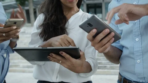 Three people standing outside with electronic devices, gesticulating actively. Stock Footage 99847941