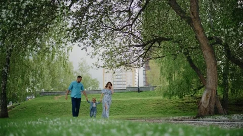 Three people stroll beneath willows with white blossoms Stock-Footage 335142993