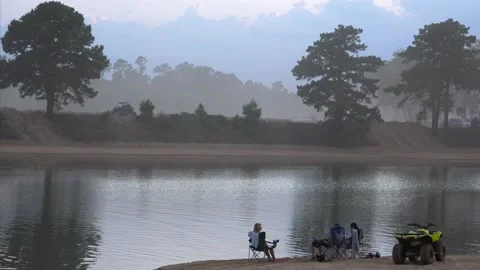 Three People Talking at the Edge of an ATV Park's Pond at Dusk - 4k Vídeos de archivo 239660599