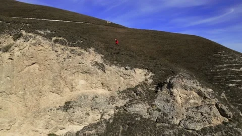Three people walk down a dangerous slope in the mountains, shooting from a drone Stock Footage 171293253