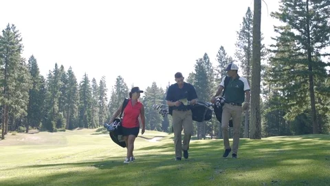 Three people walking on a golf course carrying golf bags 動画素材 76236428