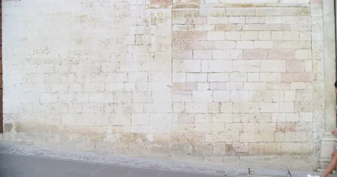 Three people walking, smiling and having fun near a brick wall in rural town of Vídeo Stock 135863082