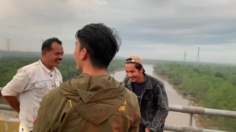 Three people were talking on the side of the bridge while resting Video stock 284913634