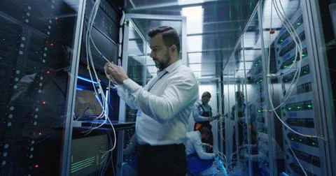Three people working in a data center with cable Stock Photos