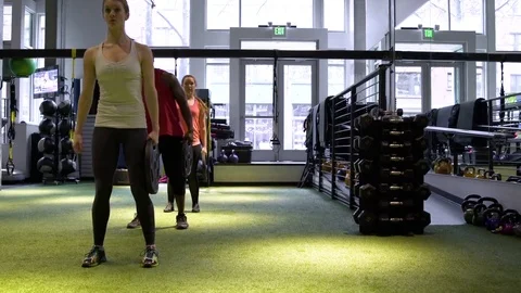 Three people working out with weight plates in a gym 動画素材 77082184