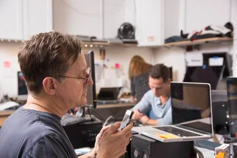 Three people working in a technology lab, with a man in the foreground looking Stock Photos