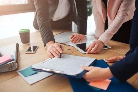 Three people working together at one talbe in room. THey look at document on Stock Photos