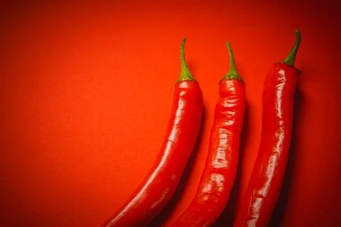 Three peppers on a red background Stock Photos