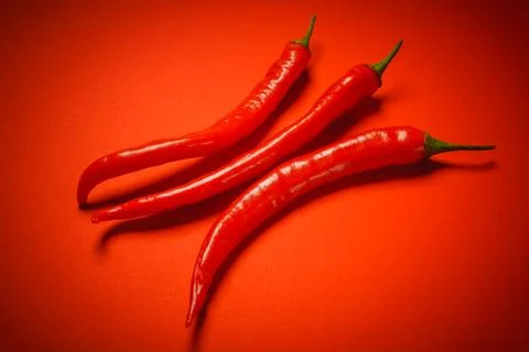 Three peppers on a red background Stock Photos