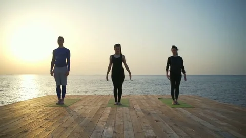 Three persons meditating on the wooden terrace slow motion Stock Footage