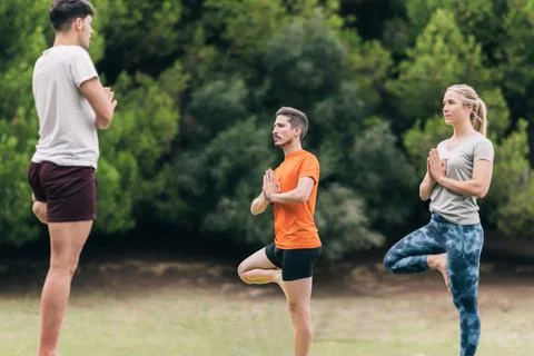 Three persons practising yoga in a park Stock Photos