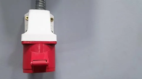 Three-phase 380 V high-voltage plug on a gray wall in a room with copy space. Stock Photos
