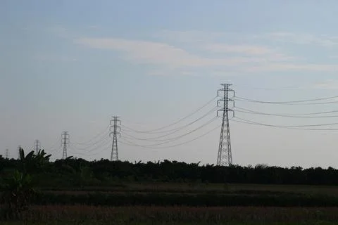 Three-phase power grid tower across the village Stock Photos