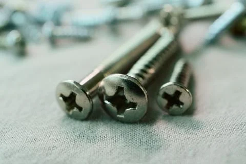 Three Phillips Screws Resting on a Fabric Surface Stock Photos