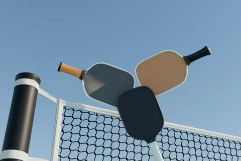 Three pickleball rackets over a net on a sports court against the sky Illustrazione stock