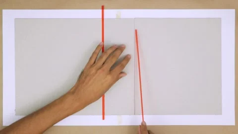 Three pieces of cardboard held together by binding rulers on a flat surface Stock Footage 280532547