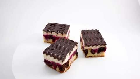 Three pieces of chocolate cake with cherry filling rotate on a white background. Stock Footage 307866006