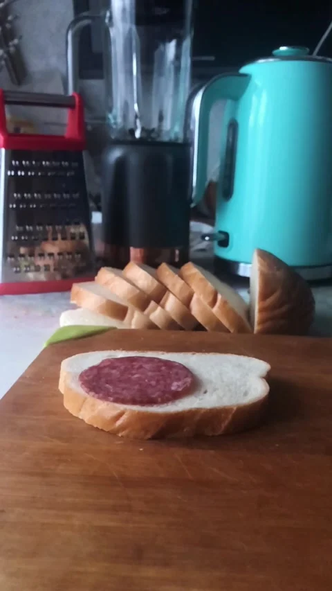 Three pieces of dried sausage fall on a piece of white bread. Stock Footage 306540366