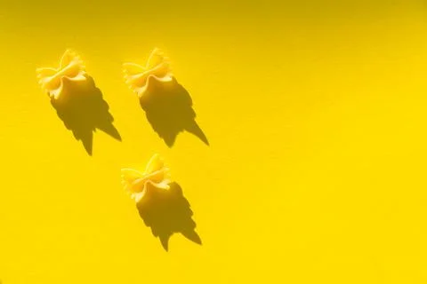 Three pieces of farfalle paste on a yellow background Stock Photos