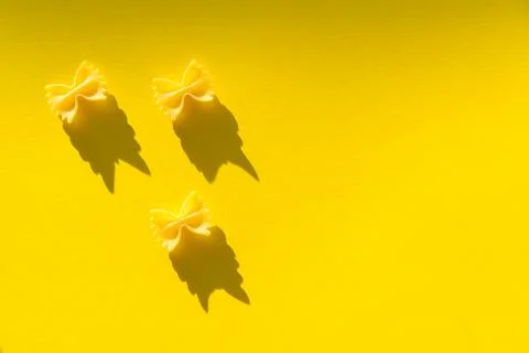 Three pieces of farfalle paste on a yellow background Stock Photos