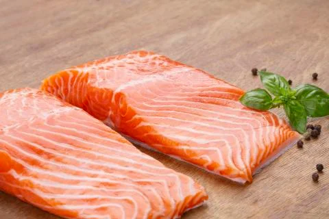 Three pieces of fresh raw salmon on a wooden board Stock Photos