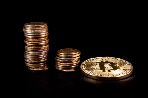 Three piles of coins in ascending order, and a Golden coin bitcoin on black l Stock Photos