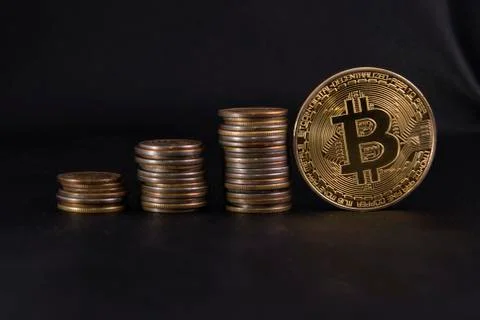 Three piles of coins in ascending order, and a Golden coin bitcoin on black l Stock Photos