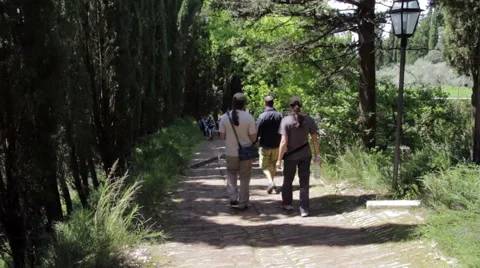 Three pilgrims walking on the paved path to reach the monastery Stock Footage 49965593
